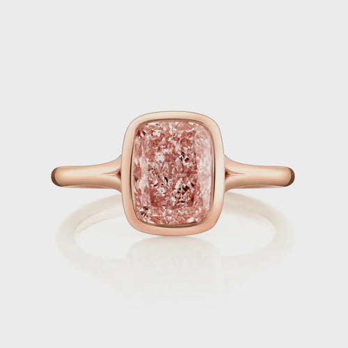 Direct top view of an elongated 2 carat fancy pink cushion cut lab grown diamond in a protective rose gold bezel setting.