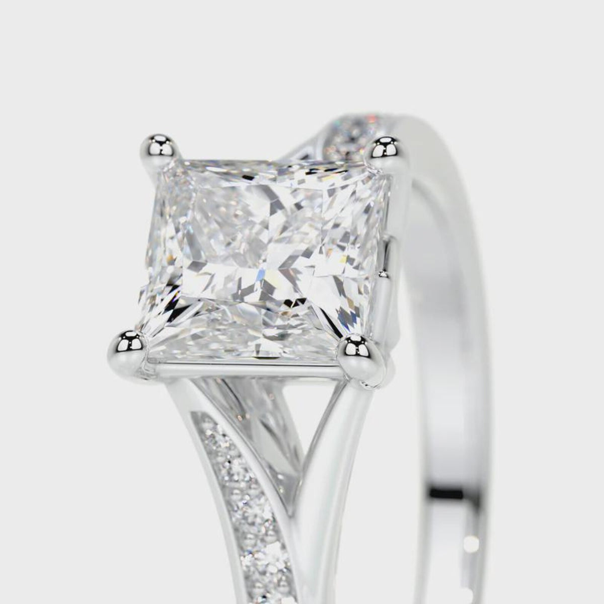 Close-up of double corner prongs and pave diamond split shoulder on a white gold princess cut ring.