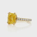 Angled side view of a 2 CT fancy yellow cushion cut lab grown diamond ring with a pavé diamond band in yellow gold.