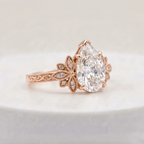 Side profile view of a 3 CT pear cut lab grown diamond ring in rose gold with floral milgrain accents and engraved band.
