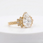 Angled side profile of a yellow gold 3 CT pear cut lab diamond engagement ring with milgrain leaf accents.