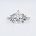 Front top-down view of a 3 CT pear cut lab grown diamond ring in polished white gold with floral halo shoulders.
