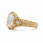 Side profile view of a yellow gold 3 CT cushion cut lab diamond ring showcasing leaf engraved shank and filigree gallery.