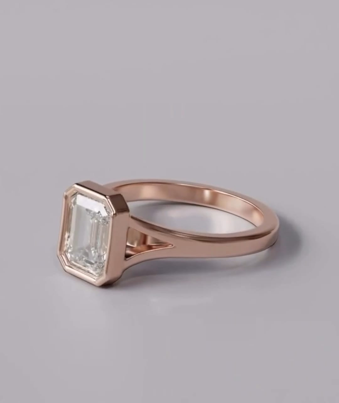 Angled view of a 3 carat emerald cut lab-grown diamond ring in a sleek rose gold bezel frame with subtle split-shoulder accents.