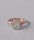 Top-down view of an IGI certified 3 CT emerald cut lab diamond encased in a modern rose gold bezel setting.