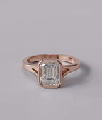 Top-down view of an IGI certified 3 CT emerald cut lab diamond encased in a modern rose gold bezel setting.