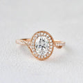 Front view of a 2 CT oval cut lab grown diamond engagement ring in 14K rose gold featuring a bypass swirl halo with milgrain border.