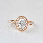 Front view of a 2 CT oval cut lab grown diamond engagement ring in 14K rose gold featuring a bypass swirl halo with milgrain border.