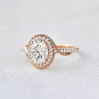 Detailed studio close-up of a rose gold bypass ring with a 2 CT oval lab diamond center and pavé-accented swirl band.