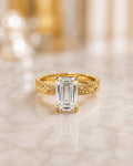 Front view of a 4 CT emerald cut lab grown diamond solitaire ring in 14K yellow gold with a hand-engraved scrollwork band.