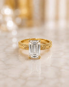 Front view of a 4 CT emerald cut lab grown diamond solitaire ring in 14K yellow gold with a hand-engraved scrollwork band.