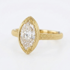 Angled side view of a 4 carat marquise cut lab diamond ring in matte yellow gold with hand-engraved leaf accents.