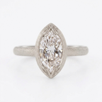 Centered top view of a 4 carat marquise cut lab grown diamond in a matte white gold bezel frame with leaf engravings.