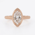Direct top view of a 4 carat marquise cut lab diamond ring in matte rose gold with leaf-carved bezel tips.