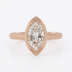Direct top view of a 4 carat marquise cut lab diamond ring in matte rose gold with leaf-carved bezel tips.