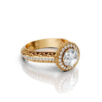 Angled perspective view of a 4 CT round lab grown diamond halo ring in yellow gold with leaf filigree and milgrain pavé band.