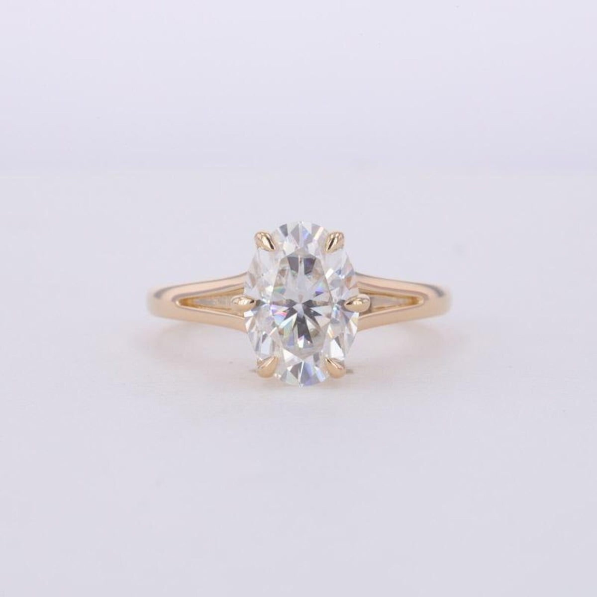 Top-down view of a 3 CT oval cut lab grown diamond set in a yellow gold split shank ring.