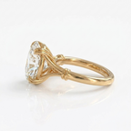Side profile angle showing the wrapped collar and double wire prongs of a yellow gold 3 CT oval diamond ring.