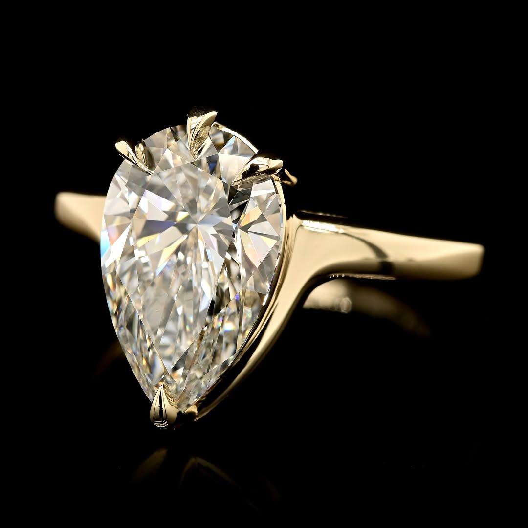 Angled view of a 3 CT pear-cut lab-grown diamond ring showcasing the high-polish yellow gold band and secure five-prong setting structure.
