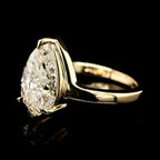 Side profile view of an IGI certified 3 carat pear shaped lab diamond solitaire ring highlighting the elegant sweep of the yellow gold mounting.