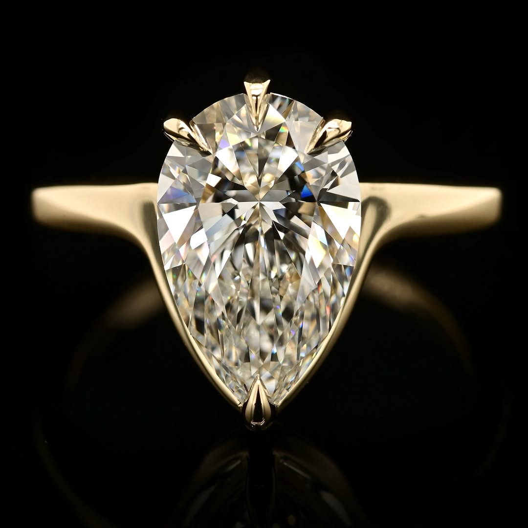 Front view of a 3 CT pear cut lab-grown diamond solitaire set in five protective yellow gold prongs on a minimal band.