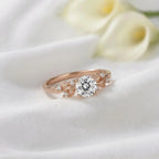 3 CT round cut lab grown diamond nature-inspired engagement ring with botanical leaf accents in rose gold on white fabric.
