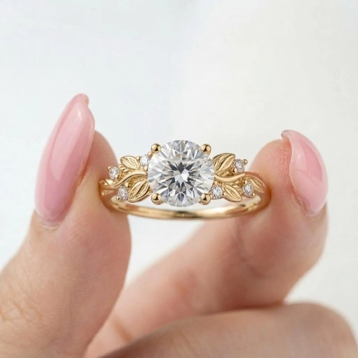 Close-up view of a 3 CT round lab grown diamond botanical engagement ring with leaf detail held between fingers.