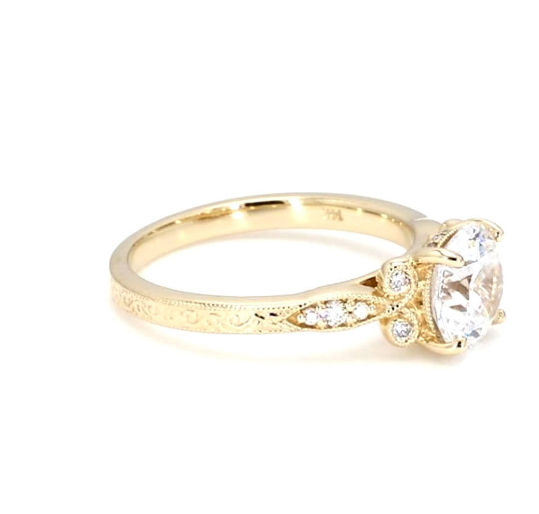 Close-up side profile of a yellow gold vintage engagement ring displaying milgrain accents and a round center diamond.