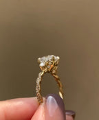 Side angle highlighting the micro-pave diamond weave on the twisted shank of a yellow gold engagement ring.