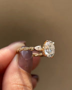 Top side view displaying the pear-cut side diamond and oval center stone set in yellow gold.