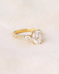 Studio flat-lay view of a 2 CT oval lab grown diamond engagement ring with pear accents on neutral fabric.