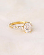 Studio flat-lay view of a 2 CT oval lab grown diamond engagement ring with pear accents on neutral fabric.