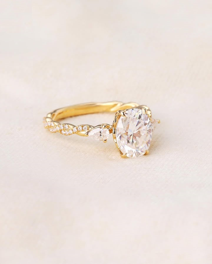Studio flat-lay view of a 2 CT oval lab grown diamond engagement ring with pear accents on neutral fabric.