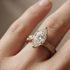 Angled on-finger view of a 4 CT marquise cut lab diamond engagement ring with milgrain accents and yellow gold band.