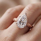On-finger view of a 4 CT pear cut lab grown diamond vintage engagement ring with hand-engraved rose gold band.