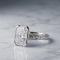 Side view of a 3 CT radiant lab grown diamond engagement ring in white gold featuring a half bezel setting and scrollwork band.