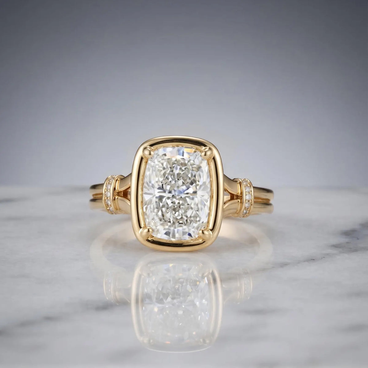 Front view of a 3 CT elongated cushion cut lab grown diamond ring in a yellow gold bezel frame with diamond cuff accents on marble.