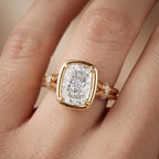 Top-down hand shot showing a 3 CT cushion cut lab diamond ring with double band split shank in yellow gold.
