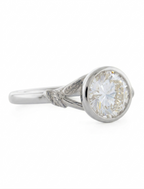 Three-quarter angle view of a 3 CT round lab diamond bezel ring with leaf shank in white gold.