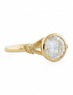 Three-quarter angle showing carved leaf shoulders and full bezel on a yellow gold 3 CT round lab diamond ring.