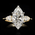 Top-down view of a 3 CT marquise-cut lab-grown diamond ring flanked by two pear-cut side diamonds on a high-polish yellow gold band.