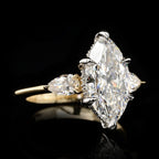 Angled view of an IGI-certified 3 carat marquise cut lab diamond three-stone ring highlighting the brilliance of the center stone and pear side accents.
