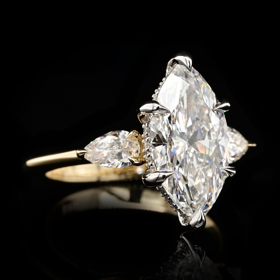Angled view of an IGI-certified 3 carat marquise cut lab diamond three-stone ring highlighting the brilliance of the center stone and pear side accents.