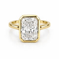 Top-down view of a 4 CT elongated radiant cut lab grown diamond ring framed in a yellow gold full bezel setting.
