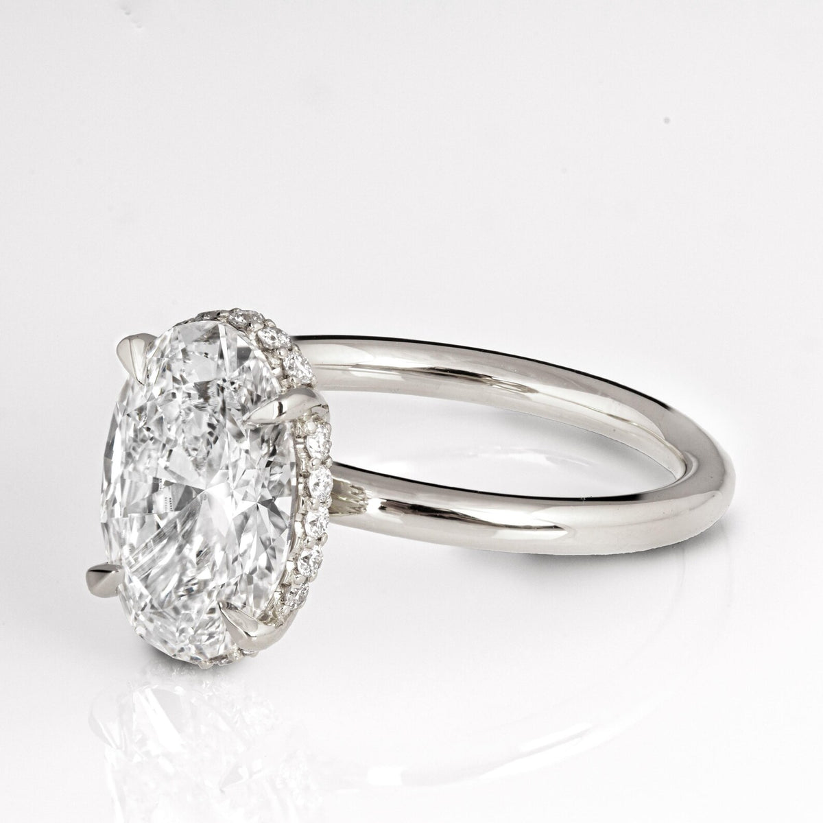 Angled view displaying the 3 CT oval lab grown diamond with delicate claw prongs and hidden halo.