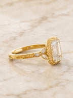 Side profile showing leaf accent diamond shoulder clusters and hand-engraved scrollwork shank on yellow gold ring.