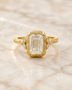 Detailed front-facing view of a 4 CT emerald cut lab grown diamond in a vintage engraved yellow gold bezel ring.