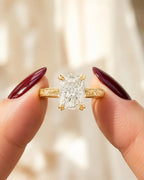 Close-up front view of a 3 CT elongated cushion cut lab grown diamond ring with double claw prongs held between fingers.