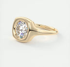 Three-quarter top angle showing the cushion-contoured gold bezel around a 3 CT round diamond.