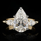 Top-down view of a 4 CT pear-cut lab-grown diamond engagement ring flanked by two smaller pear side diamonds on a high-polish yellow gold band